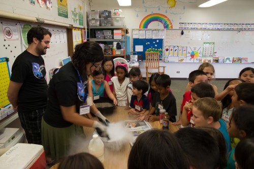Subaru Astronomer Julien Lozi (left, black shirt) and Gemini Public Information and Outreach (PIO) staff Alyssa Grace (right, black shirt), modeled comets for students at Waiākeawaena using dry ice, dirt, colored sand, and corn syrup.